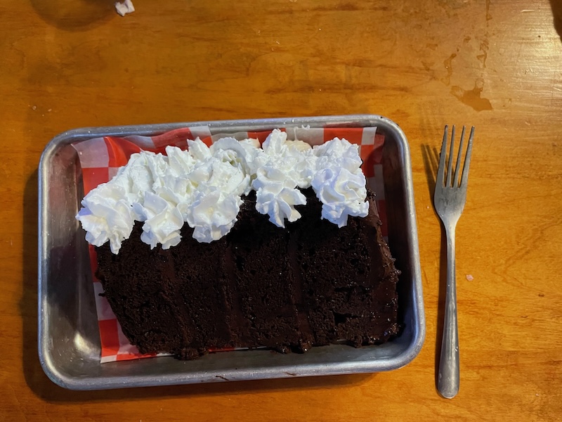 Large slice of Death by Chocolate Cake topped with whipped cream